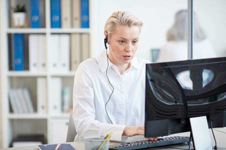 femme portant une oreillette et tapant sur le clavier de son ordinateur