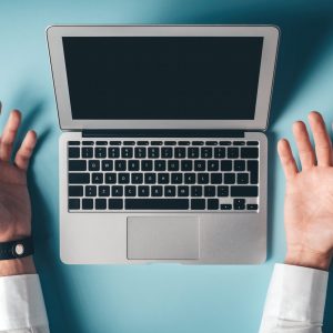 mains d'homme ouvertes avec un ordinateur au centre sur fond bleu